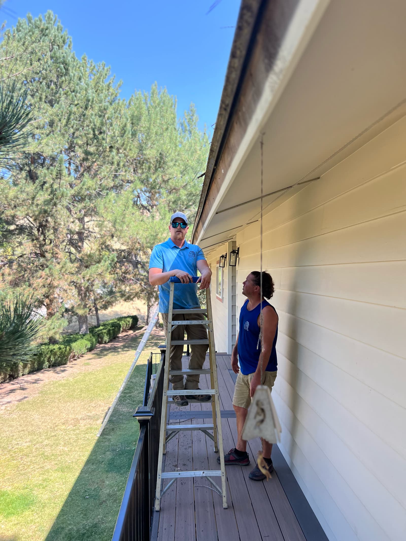 Two of the crew looking over the eave of a deck before the old gutter comes down