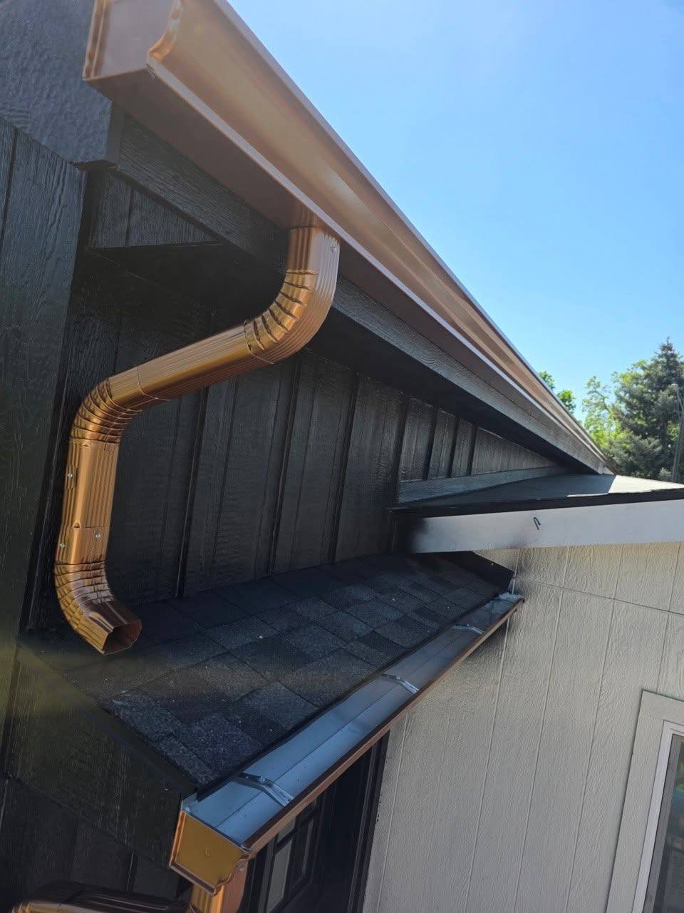 Downspout elbow running clean against dark siding
