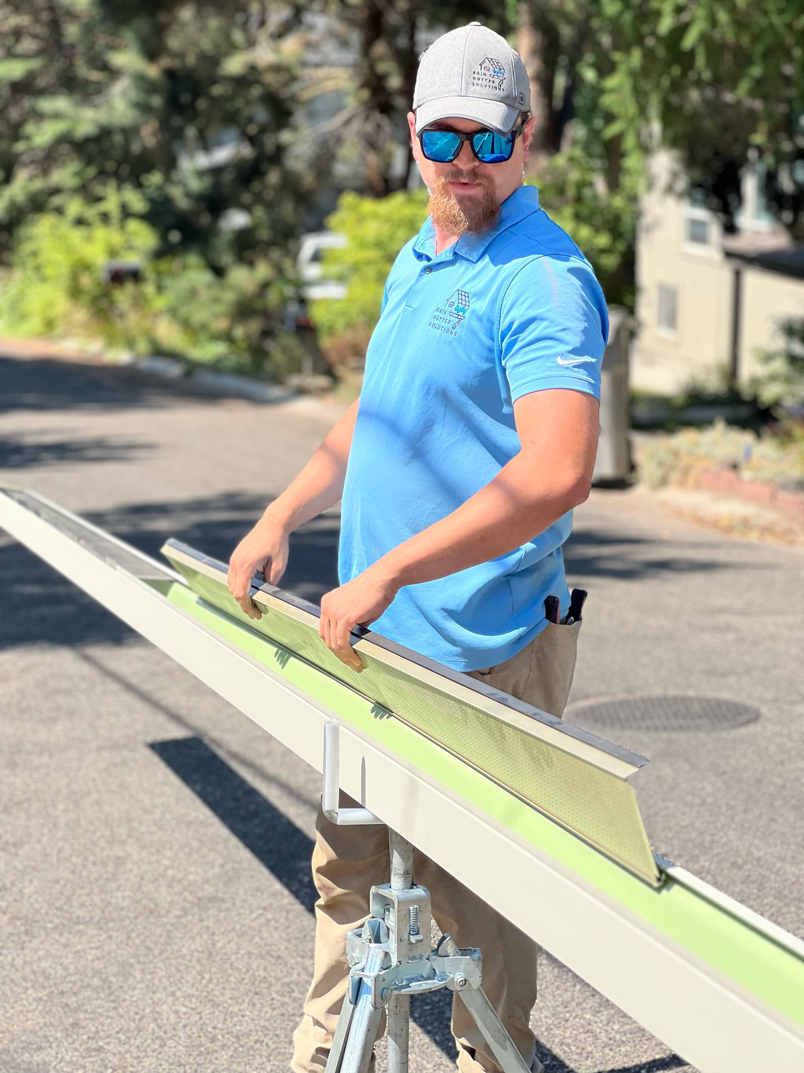 Fitting a gutter guard into a length of seamless gutter on the stand before it goes up on the roof