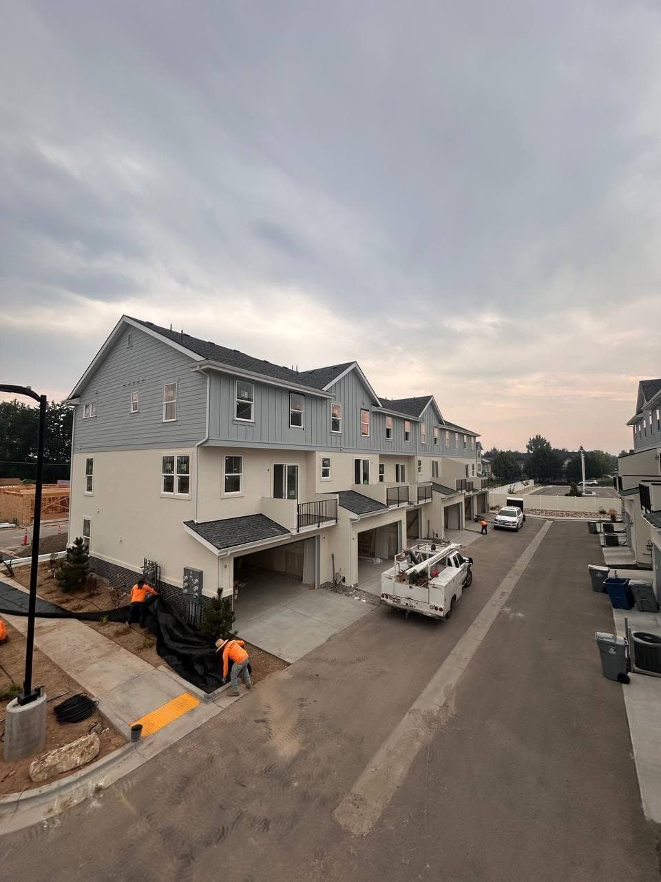 Row of townhomes under construction at dusk with gutter work in progress