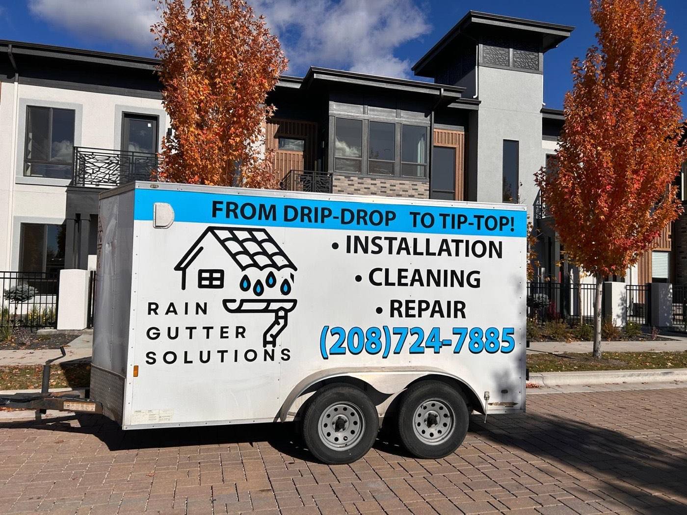 Rain Gutter Solutions branded trailer parked outside a row of Treasure Valley townhomes